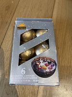 Front view of a silver box containing 6 gold floating candles visible through windows.