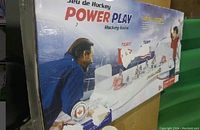 Box of Power Play hockey table top game showing two players playing the game on the box art, with some corner and edge damage visible.