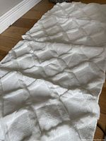 Cream textured throw pillow covers laid out flat on wooden floor, showing diamond pattern.