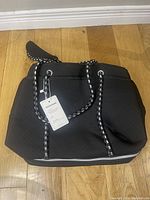 Front view of the black neoprene tote bag with a visible Lands' End tag and padded black and white rope handles.