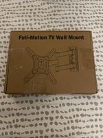 Photo of sealed cardboard box labeled 'Full-Motion TV Wall Mount' showing illustration of mount's articulating arm and mounting plate.