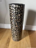 Full view of tall cylindrical vase showing intricate shell inlay pattern on black base.