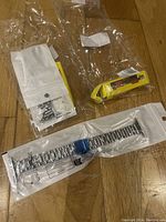 Photo of two individually packaged silver metal link watch bands compatible with Apple Watch on wooden floor.
