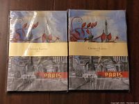 Two unopened Christian Lacroix Paris notebooks front view showing artistic Paris-themed cover design with 'PARIS' text.
