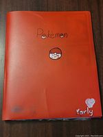 Front cover of the red Pokemon binder showing hand-drawn Pokemon text and Pokeball graphic, signed Karly