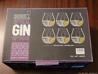 Top view of the unopened purple and black box containing 6 new Riedel Optical Gin glasses. Box front shows images of the glass shape filled with gin and lemon garnish.