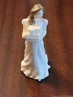 Front angle view of the Royal Doulton porcelain figurine of a girl holding Christmas parcels showing detailed facial features and dress texture.