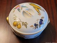 Top view of the covered casserole dish showing fruit patterns and gold-tone handles.