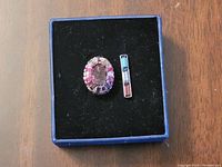 Open Swarovski box showing the oval silver ring with purple and pink stones against black cushioning.