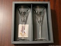 Two crystal champagne glasses with detailed cut designs in original box with divider.