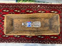 Top-down view of the large rectangular wooden tray on a patterned carpet with a water bottle for scale.