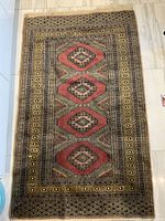 Full view of the vintage Persian carpet laid flat on floor showing the main field with four red geometric medallions and multi-banded borders.