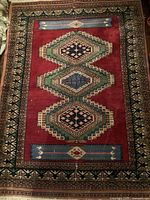 Full view of Persian carpet showing central geometric diamond medallions and multi-colored border design.