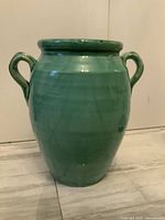 Front view of large turquoise ceramic urn with two handles.