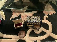 Photo of three small vintage boxes including floral rectangular box, blue geometric square box with compact, and round brown leather box