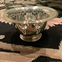 Side view of the antique sterling silver pierced bowl showing intricate pierced design on the sides and reflective polished surface.
