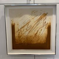 Front view of framed abstract mezzotint print showing ochre tonal strokes and dynamic lines inside white matte and silver frame.