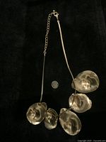 Full shot of the vintage metal costume jewelry necklace laid out with coin for scale