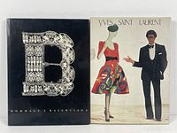 Front covers of the two vintage fashion books - 'Hommage a Balenciaga' with black cover and ornate silver B, and 'Yves Saint Laurent' with illustrated cover.