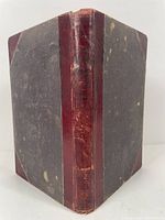 Front cover and spine showing wear, red leather corners and spine with cloth boards showing spotting and wear.