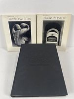 Three Edward Weston photography books. Two softcovers titled 'The Daybooks of Edward Weston' (Mexico and California) and one black hardcover titled 'Leaves of Grass' with embossed text.
