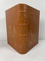Brown leather bound book with gold embossed text and illustrations on cover and spine, titled Emma by Jane Austen, illustrated by Fritz Kredel.