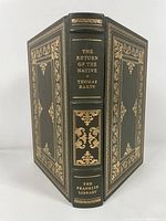 Front and spine view of the limited edition hardcover showing detailed gold embossed decoration and title on dark green leather binding.