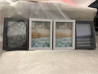 Four wooden picture frames standing side by side on a white surface. Two are black, two are white. All are sealed and measure 6x8 inches.
