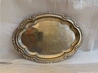 Full view of the ornate antique steel plate showing engraved floral and scroll patterns across the flat surface with a shaped scalloped rim.