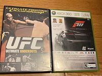 Front covers of UFC Ultimate Knockouts DVD and Forza Motorsport 3 Xbox 360 game cases sitting side by side on wooden surface.