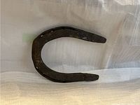 Top and angled view of the horseshoe showing its shape, surface texture, and rusty patina.