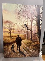 Photo of framed landscape artwork measuring 20 x 27.5 inches showing man, dog, trees and bird in soft warm light.