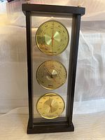 Full view of Sabra framed instrument with three dials for temperature, barometer, and hygrometer in gold tones and black frame.