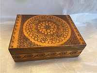 Top view photo of the rectangular wooden box showing the detailed circular mandala carved design on the lid with floral and swirl elements.