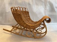 Side angle view of the wooden wicker sled decoration on plain background showing the curled front and woven seat