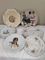 Photo showing all six decorative plates with various floral and child/portrait designs.