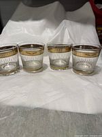 Four whisky glasses with gold rims and a gold band around the top inscribed 'CHADIAN DISTILLERS' in white lettering. Glasses are clear with textured lower portions and appear to be in excellent condition.