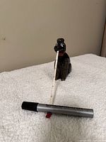 Full front view of the black poodle pin cushion with measuring tape extended, showing the tape extended from the mouth.