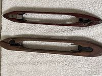 Top view of two wooden loom shuttle guides showing overall shape, metal tips, and guide rods.