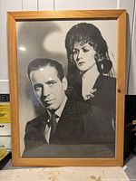 Framed black and white print of Lucille Ball and Humphrey Bogart in a light wood frame, 20 x 27 inches.