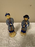 Pair of Occupied Japan ceramic figurines of a male and female in traditional East Asian style clothing, posed standing on bases.