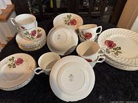Ridgway Anniversary Rose ironstone dinnerware set with plates, cups, and saucers, all featuring rose floral motif and ribbed edges arranged on a table.
