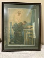 Framed artwork showing a soldier kneeling and being blessed by a religious figure. Dark wooden frame with double matting in green and off-white.