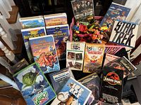 Photo of VHS tapes and colorful toy vehicles and figurines showing various animated and popular series titles.