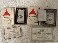 Three Zippo lighters displayed with their original boxes and two guarantee cards, highlighting condition, branding, and included documentation.
