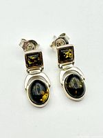 Front view of both sterling silver amber earrings showing the square and oval amber stones with silver frames.