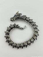 View of the full articulated dragon bracelet coiled to show scale detail and clasp hook