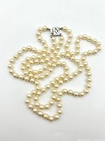 Top-down view of entire double-strand pearl necklace arranged loosely to show length and clasp