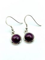Front view of pair of round ruby cabochon earrings in sterling silver bezels with French hook clasps on white background.
