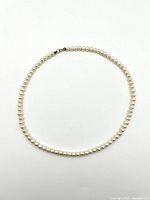 Full view of the pearl necklace laid flat showing the entire length and clasp.